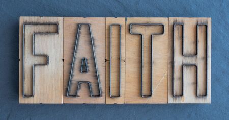 Old wood and steel number plate dies spell out the word FAITHの写真素材