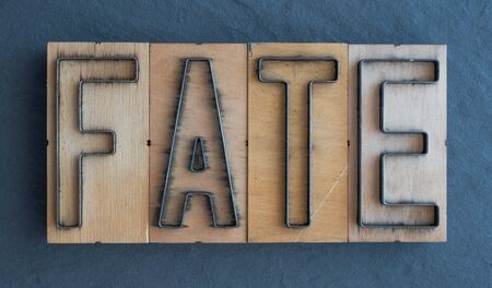 Old wood and steel number plate dies spell out the word FATEの写真素材