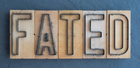 Old wood and steel number plate dies spell out the word FATEDの写真素材