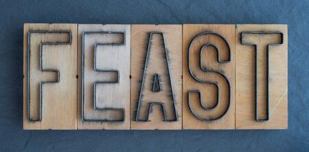 Old wood and steel number plate dies spell out the word FEASTの写真素材