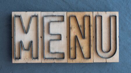 Old wood and steel number plate dies spell out the word MENUの写真素材