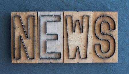 Old wood and steel number plate dies spell out the word NEWSの写真素材