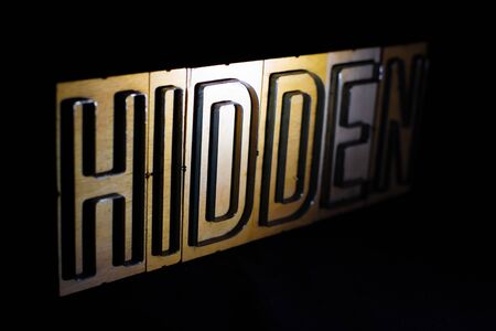 Old wood and steel number plate dies spell out the word HIDDENの写真素材