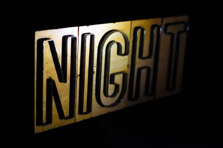 Old wood and steel number plate dies spell out the word NIGHTの写真素材