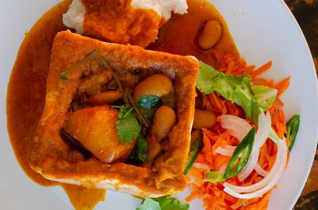 A Durban Bunny Chow - or, in this case, a vegerarian quarter bean bunny - served with sambals. This is an iconic Durban meal consisting of a section of a loaf of bread hollowed out and filled with bean curry and gravy. The sambals are grated carrot with chopped chilli. The meal is traditionally eaten with one's fingers.の写真素材