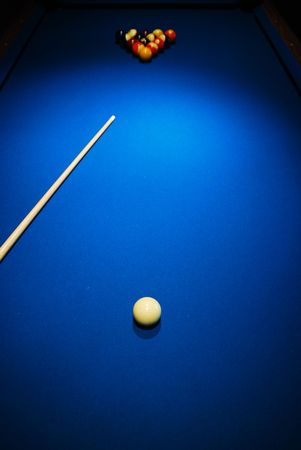 A pool table with a cue stick and balls.