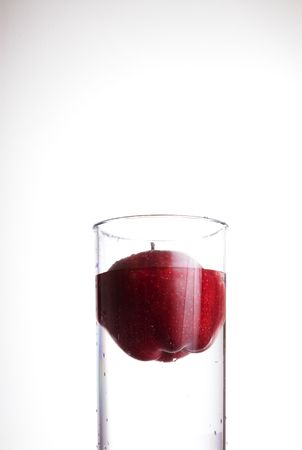 A red delicious apple floating in a glass of waterの写真素材