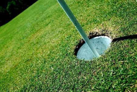 A golf hole on a green of a golfcourse with focus on the flag.