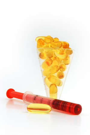 fish oil caplet filled a cup and a dropper with red colour cough syrupの写真素材