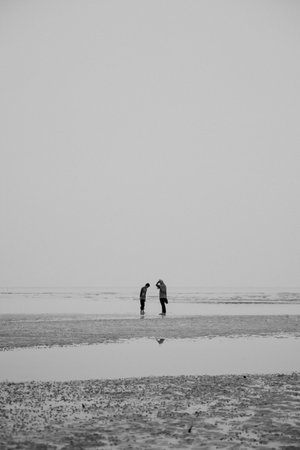 Black and white image of a sisters walking on the beach at low tideの写真素材