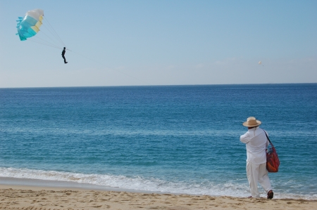 Beach vendor walking along water's edge with parachuteの写真素材