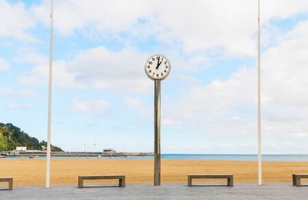A nice clock between two benches on a beach in the Basque Country in Spainの写真素材