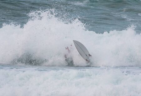Surfer swallowed by a big wave on a beach on the north coast of Spainの写真素材