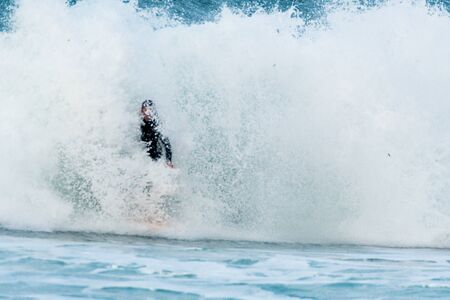 Surfer swallowed by a big wave on a beach on the north coast of Spain
