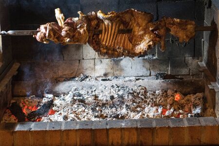Half-lamb barbecue inserted in an iron sword circling the burning coalの写真素材