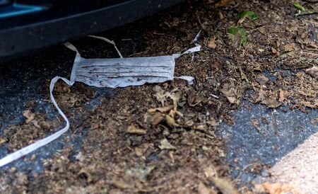 Used and very dirty mask lying on the floor. It's been there a while. The debris from covid19....