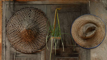 Traditional Chinese hat made of bamboo hanging on wooden window, retro decoration backgroundの写真素材