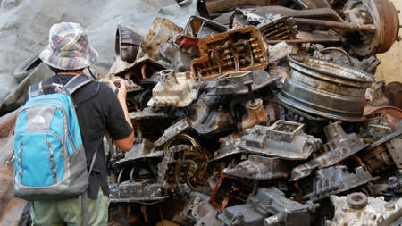 Woman tourist take a photo heap of old machine parts in second hand machinery shopの写真素材