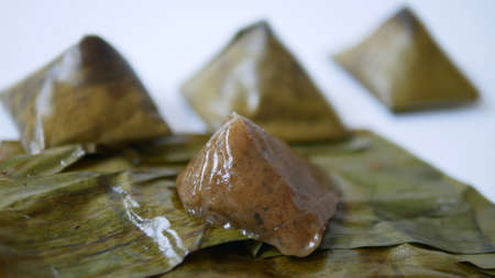 Stuffed dough pyramid dessert called Ka-Nhom-Tian isolated on black background, Thai dessert  wrapped in banana leavesの写真素材