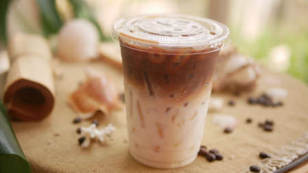 Ice coffee and milk in takeaway cup with shell-shaped and coffee bean background.の写真素材