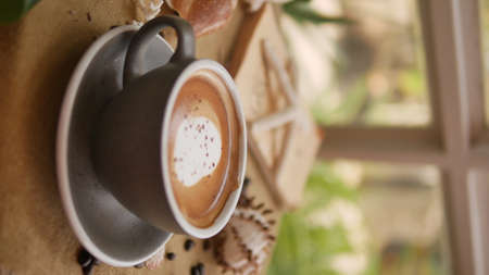 A cup of cappuccino with shell-shaped and coffee bean background.の写真素材