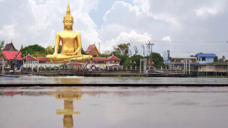 April 6 2021 - Nonthaburi, Thailand : Big golden buddha statue with reflection on wet table at Wat Bangjak located by the Chao Phraya River, Thailandのeditorial素材