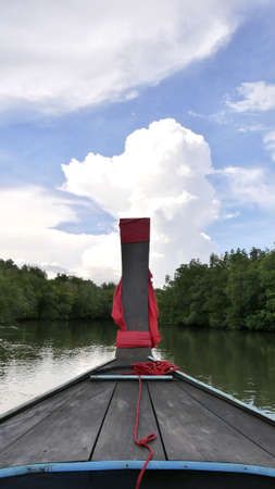 Front view of prow long tail boat on the sea with mountain against blue sky.の写真素材
