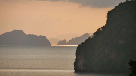 Dramatic sunset sky above the sea with silhouette mountain in foreground, beautiful seascape after sunset.の写真素材