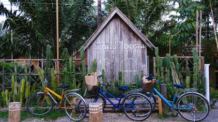 June 29 2021 - Ranong, Thailand : Two bicycle parking in front of wooden sign Baan Rai I Arun in Thai, The famous farm stay in Thailand.のeditorial素材