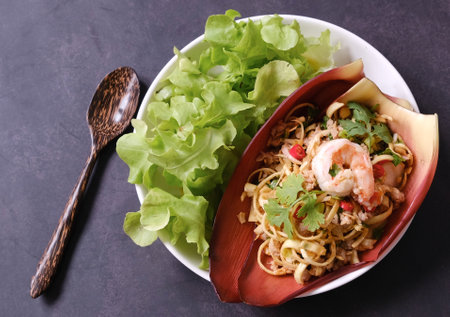 Top view Thai banana blossom spicy salad with shrimp and ground pork on banana blossom leaves on black background (Yum Hua Plee).の写真素材