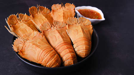 Big boiled crawfish (crayfish)  in a dish with spicy sauce isolated on black background.の写真素材