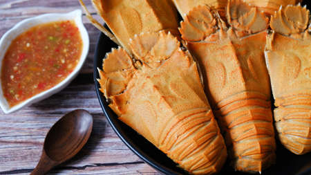 Big steamed crawfish (crayfish)  in a dish with spicy sauce isolated on wooden background.の写真素材