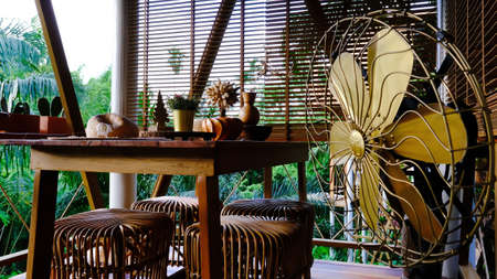 Beautiful terrace or balcony with wooden table, rattan chair and retro brass fan.の写真素材