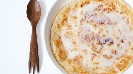 Chapati a thin pancake known as roti topping with sweet condense milk on white background, Indian traditional street food.の写真素材