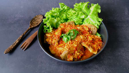 Top view  sea bass snapper fillet with garlic chilli spicy sauce on black background, Thai style food.の写真素材