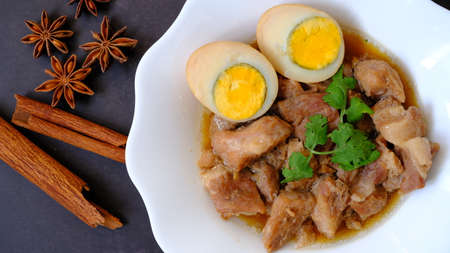 Top view egg and pork stew (braised) with dried anise and cinnamon on black background.