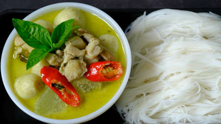 Top view green curry chicken and fish ball with rice noodle (vermicelli) on black  background.