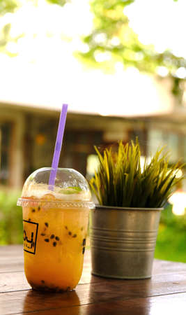 Passion fruit drink in plastic togo cup with grass wheat in aluminium pot plant.の写真素材