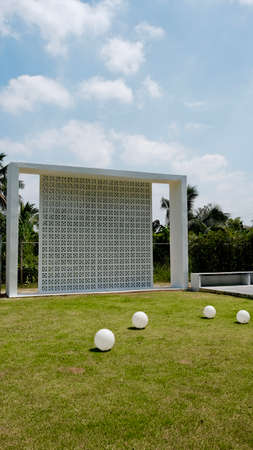 Simple wall architecture with bulb light decoration in grass field.の写真素材