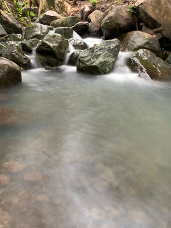 Long exposure on river flowing through rocks in forest.の写真素材
