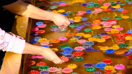 Hands of people floating colorful candle floating on water for pray at the temple.の写真素材