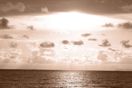 Sunbeams breaking through the sky in a seascape at sunset.の写真素材