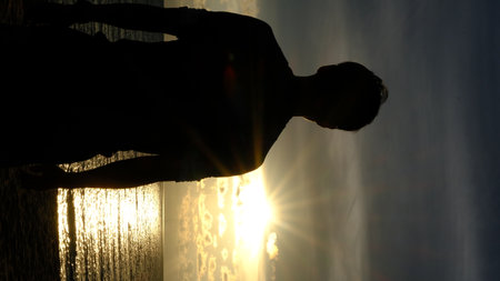 Silhouette young man looking at sea while sunset view on beach.の写真素材