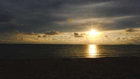 Sunbeams breaking through the sky in a seascape at sunset.の写真素材