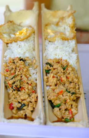 Selective focus rice with basil chicken with fired egg in bamboo container.の写真素材