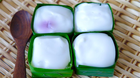 Close-up Thai Pudding with Coconut topping called Khanom Tako in coconut leaf isolated on white background.の写真素材