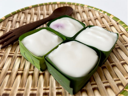 Close-up Thai Pudding with Coconut topping called Khanom Tako in coconut leaf isolated on white...
