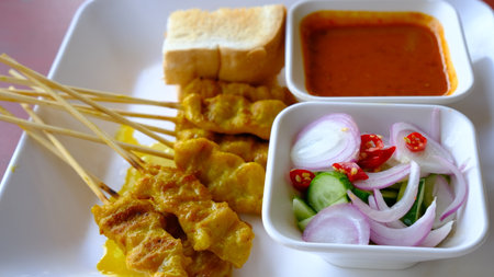Grilled pork or satay pork served with peanut sauce, cucumber salad sweet  and grilled toast, Asian appetizer.の写真素材