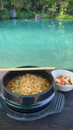Instant noodle in hot bowl and kimchi on the river background.の写真素材