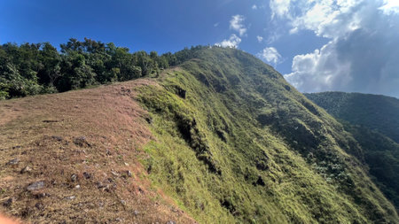 Mountain trail leading along the mountain ridge of beautiful mountains with green grass and cloudscape at Tak province, Thailand.の写真素材